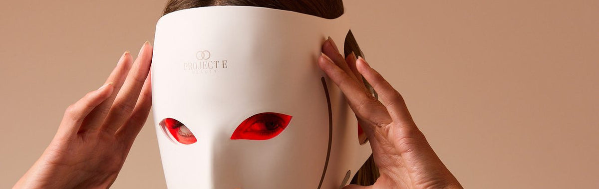 Woman adjusting the LumaLux Face V2 3D LED red light therapy mask with both hands